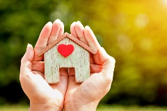Hands holding a house with a heart.